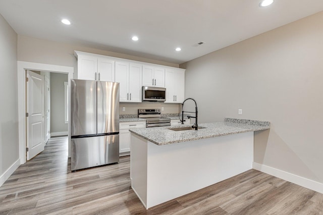 kitchen featuring white cabinetry, sink, light stone counters, stainless steel appliances, and light hardwood / wood-style flooring