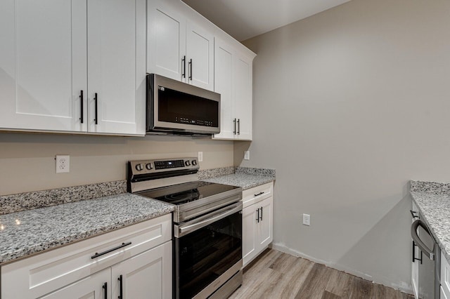 kitchen with stainless steel appliances, light stone countertops, light hardwood / wood-style flooring, and white cabinets