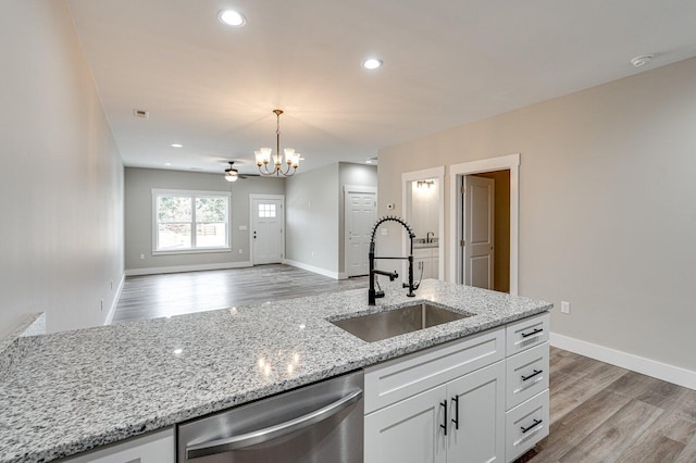 kitchen featuring sink, white cabinetry, stainless steel dishwasher, pendant lighting, and light stone countertops