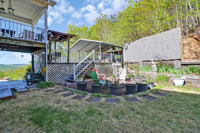 view of yard with fence, a wooden deck, and stairs