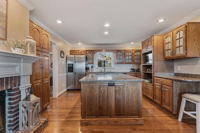 kitchen featuring a kitchen island, light hardwood / wood-style floors, dark stone counters, and appliances with stainless steel finishes