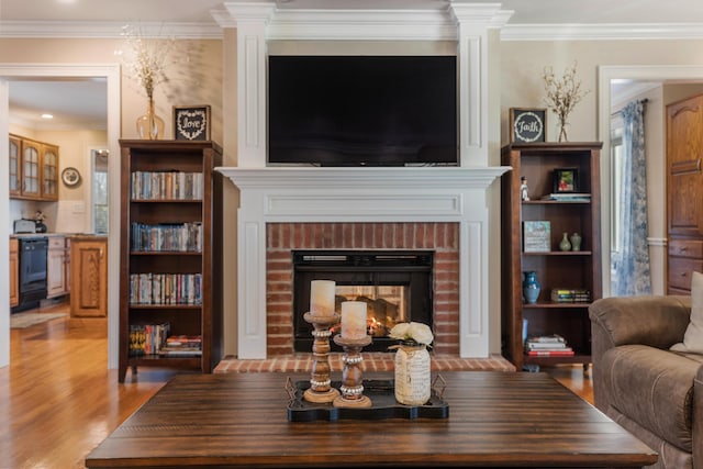 living room with crown molding, a brick fireplace, and light hardwood / wood-style floors