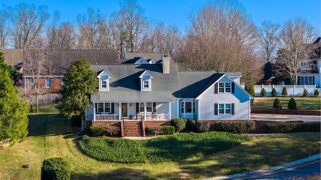 cape cod home featuring a porch and a front lawn