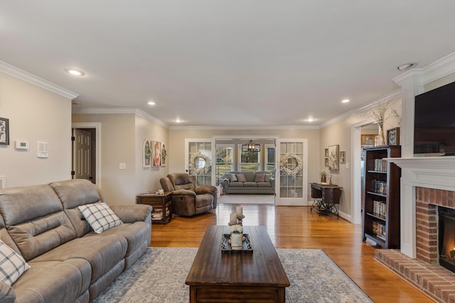 living room with a brick fireplace, ornamental molding, and light wood-type flooring