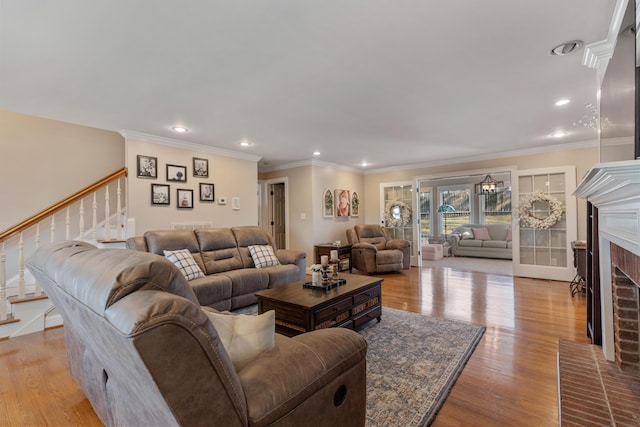 living room featuring ornamental molding, a fireplace, and light hardwood / wood-style floors