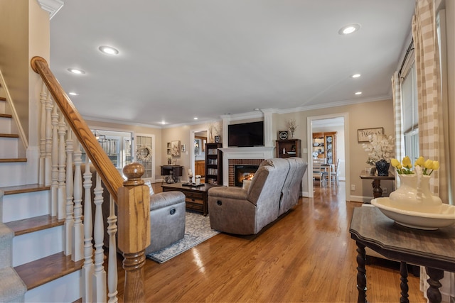 living room featuring a brick fireplace, crown molding, and light hardwood / wood-style floors