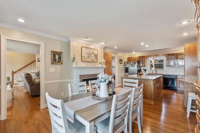 dining area featuring hardwood / wood-style flooring, ornamental molding, a brick fireplace, and sink