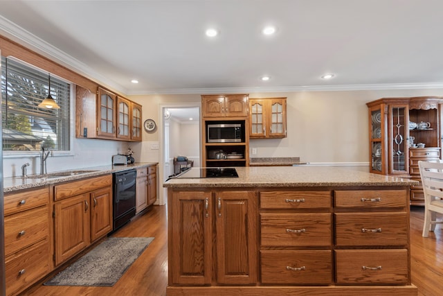 kitchen featuring sink, ornamental molding, a center island, black appliances, and light wood-type flooring