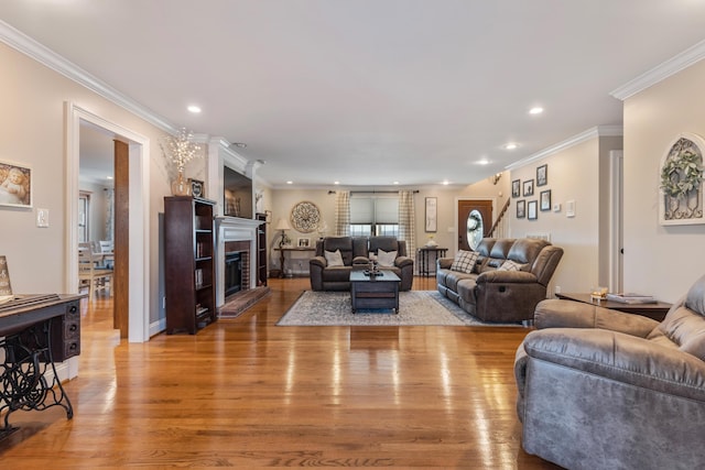 living room featuring ornamental molding, a fireplace, and light hardwood / wood-style floors