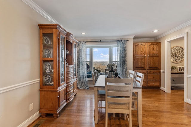 dining room with crown molding and light hardwood / wood-style flooring