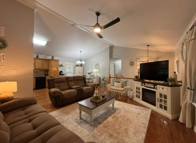 living area with crown molding, vaulted ceiling, ceiling fan with notable chandelier, and wood finished floors