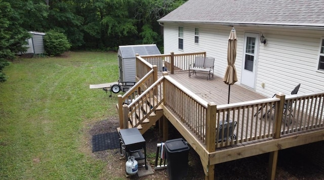 wooden deck featuring a storage unit, an outdoor structure, a lawn, and stairs