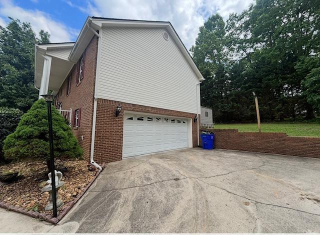 view of home's exterior with concrete driveway, brick siding, and a garage