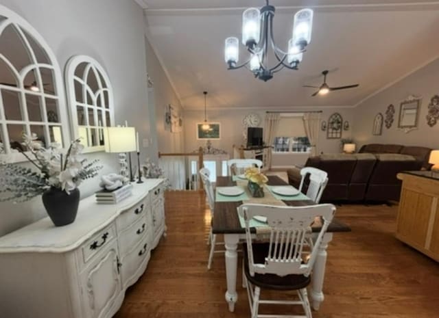 dining room with crown molding, vaulted ceiling, wood finished floors, and ceiling fan with notable chandelier
