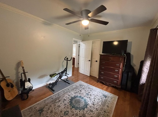 workout room featuring dark wood-type flooring, ornamental molding, baseboards, and ceiling fan