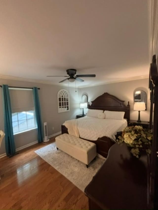 bedroom with crown molding, a ceiling fan, baseboards, and wood finished floors