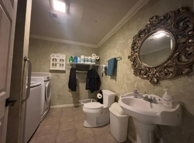 bathroom with tile patterned flooring, baseboards, toilet, ornamental molding, and washer and dryer