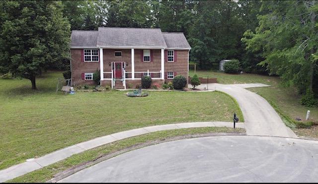split foyer home featuring curved driveway and a front lawn