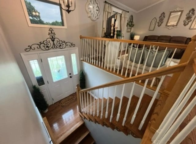 stairway featuring ornamental molding, wood finished floors, and a chandelier