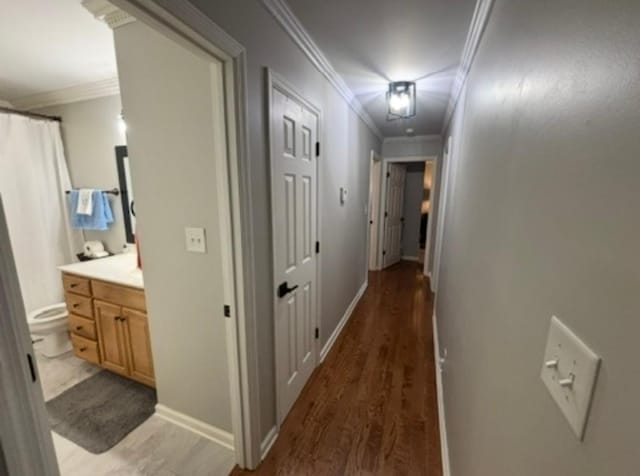 corridor with crown molding, baseboards, and wood finished floors