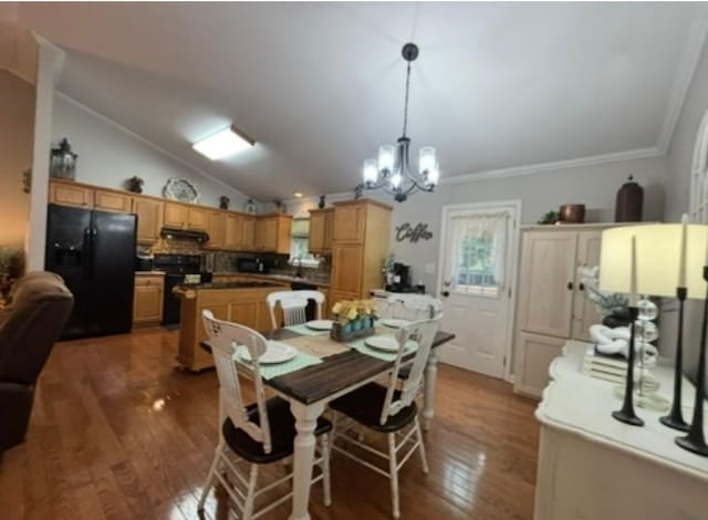 dining area with crown molding, lofted ceiling, wood finished floors, and a notable chandelier