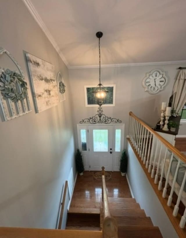 entrance foyer with ornamental molding, wood finished floors, and stairway