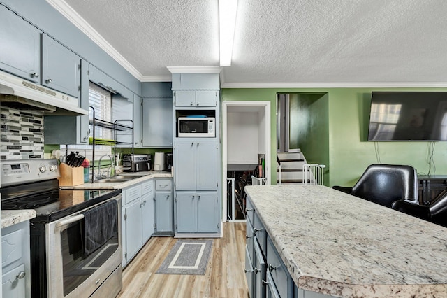 kitchen with white microwave, under cabinet range hood, stainless steel electric stove, and light countertops