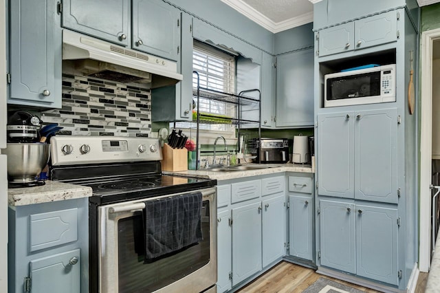 kitchen with white microwave, under cabinet range hood, light countertops, ornamental molding, and stainless steel electric range oven