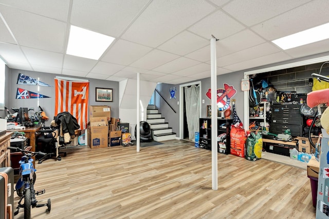 finished basement with a paneled ceiling, stairway, and wood finished floors