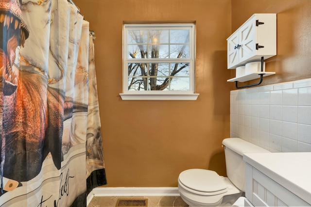 bathroom with visible vents, toilet, tile patterned floors, vanity, and tile walls