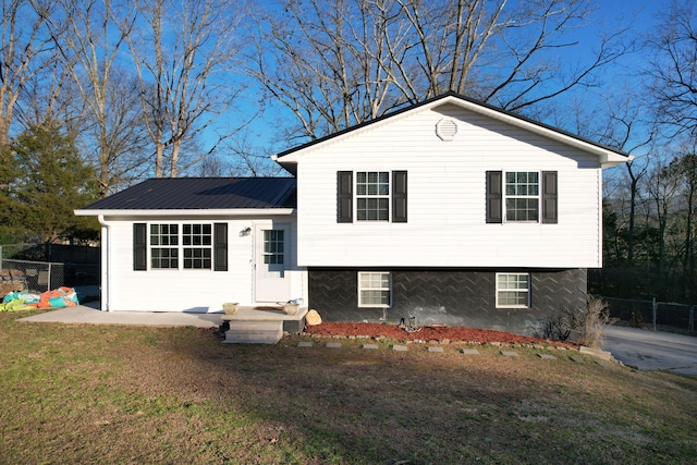 tri-level home featuring metal roof, a front lawn, a patio, and fence