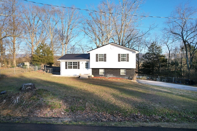 split level home with a front lawn, fence, and stucco siding