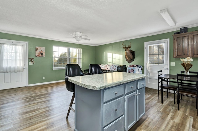 kitchen with a center island, gray cabinets, light countertops, light wood-style flooring, and plenty of natural light