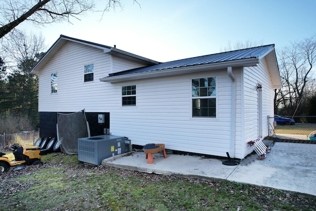 back of property featuring cooling unit, metal roof, a patio, and fence