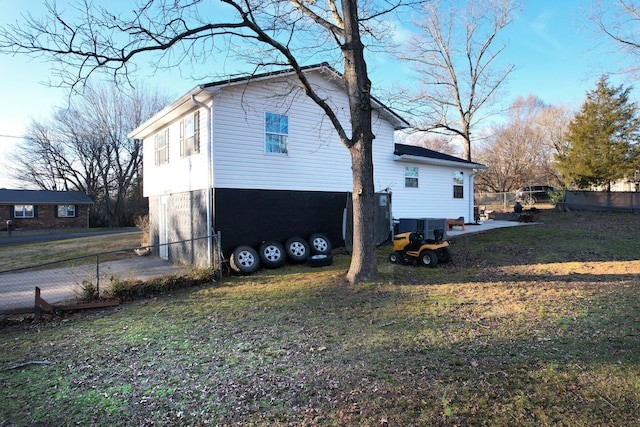 view of property exterior with a lawn, fence, and cooling unit