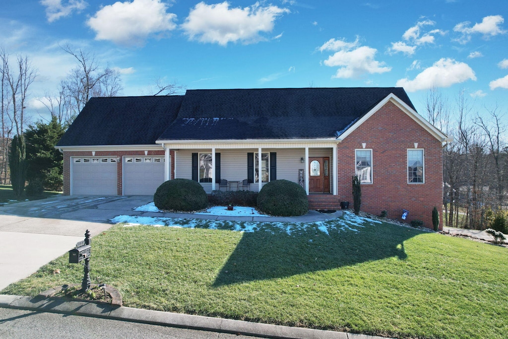 view of front of property with a porch, a garage, and a front lawn