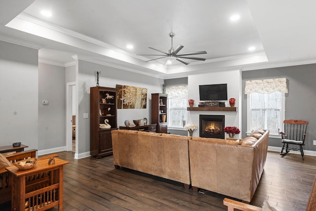 living room with dark wood-type flooring, plenty of natural light, ceiling fan, and a raised ceiling