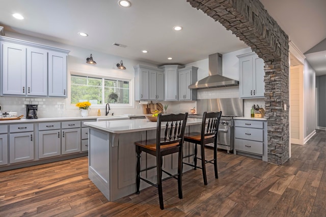 kitchen with gray cabinetry, dark hardwood / wood-style floors, and wall chimney range hood