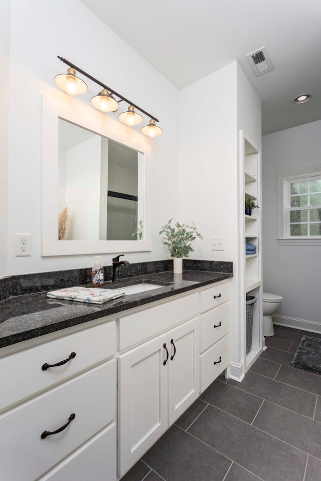 bathroom with toilet, vanity, and tile patterned floors