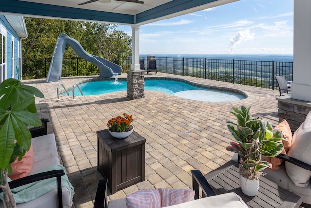 view of pool featuring a water slide, ceiling fan, a water view, and a patio