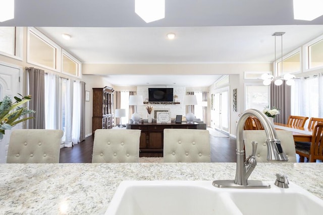 kitchen featuring light stone countertops, sink, pendant lighting, and dark wood-type flooring