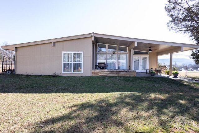 rear view of property featuring french doors, ceiling fan, and a yard