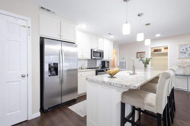 kitchen featuring a breakfast bar, pendant lighting, white cabinetry, a kitchen island with sink, and stainless steel appliances