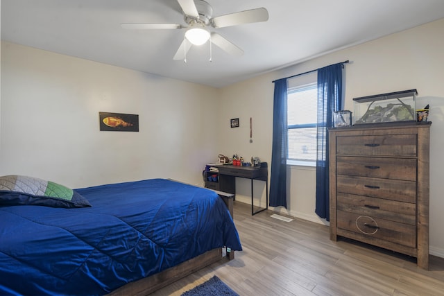 bedroom with light wood finished floors, baseboards, and a ceiling fan