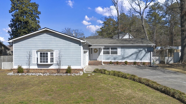 ranch-style home featuring driveway, fence, and a front lawn