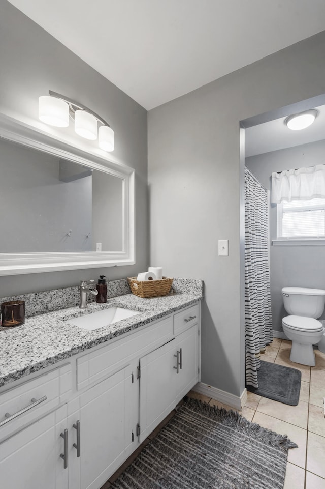 bathroom featuring baseboards, vanity, toilet, and tile patterned floors