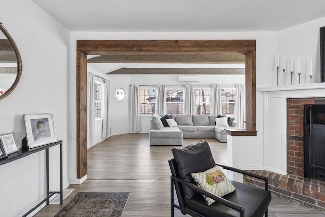 living room featuring a fireplace, baseboards, and wood finished floors