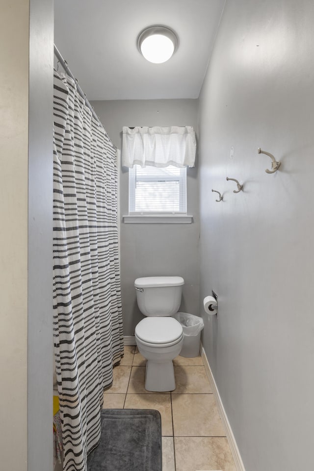 full bathroom featuring toilet, a shower with curtain, baseboards, and tile patterned floors