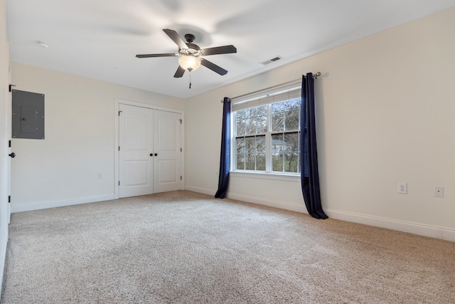 empty room with light carpet, electric panel, and ceiling fan