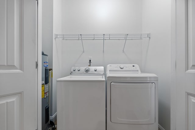 washroom with washing machine and clothes dryer and water heater